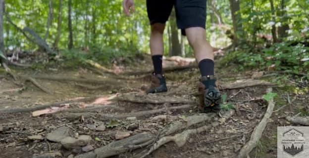blog-img-1735398996433 Testing the Merrell Moab 3 traction on a steep incline, demonstrating how the Vibram® TC5+ 5mm lugs bite into loose roots for maximum uphill propulsion and stability.