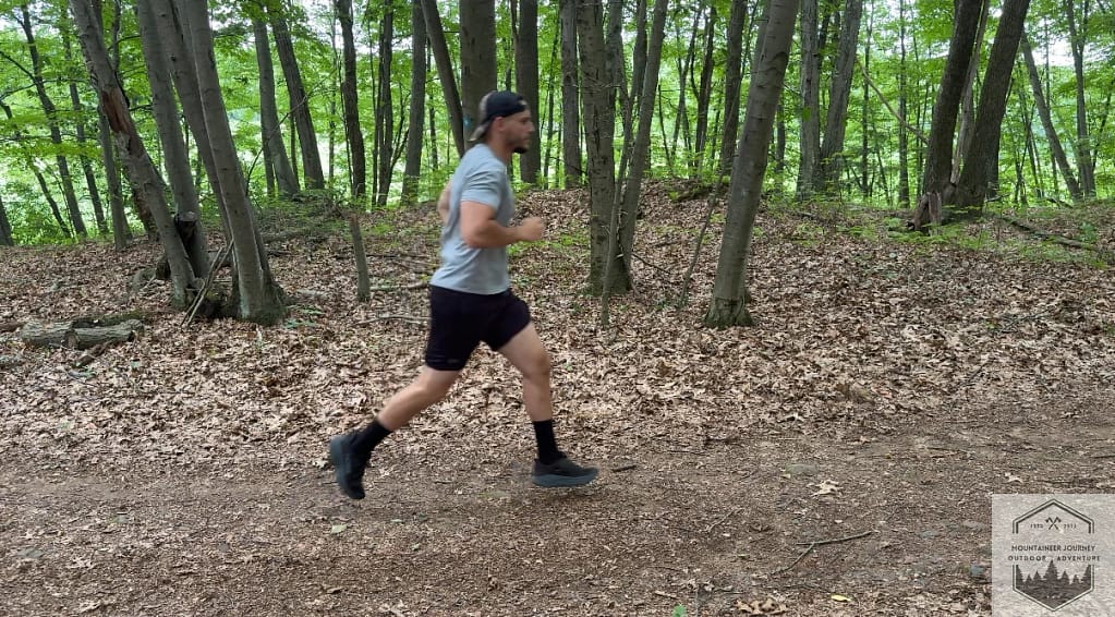 Actively testing the Hoka Challenger 8 on a technical trail, demonstrating the Meta-Rocker geometry's ability to facilitate a smooth, propulsive gait on uneven terrain.