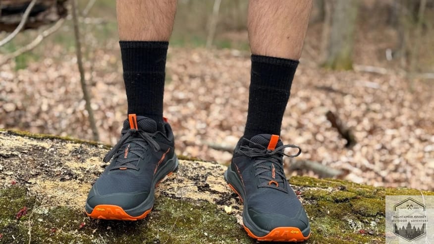 Altra Lone Peak 9+ being tested for stability and traction while standing on a fallen tree trunk.