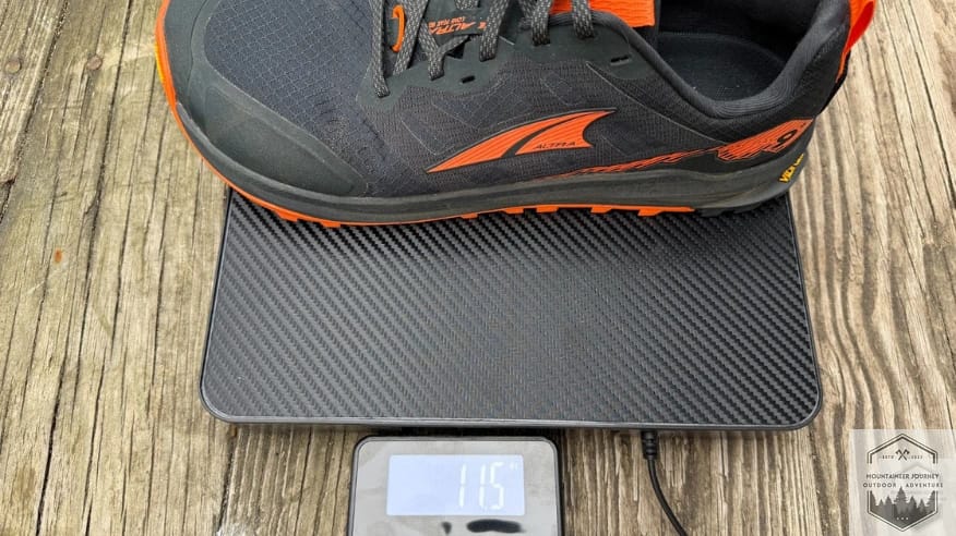Weighing the Altra Lone Peak 9+ on a digital scale at 11.5 oz to verify real-world weight for a trail running shoe review.