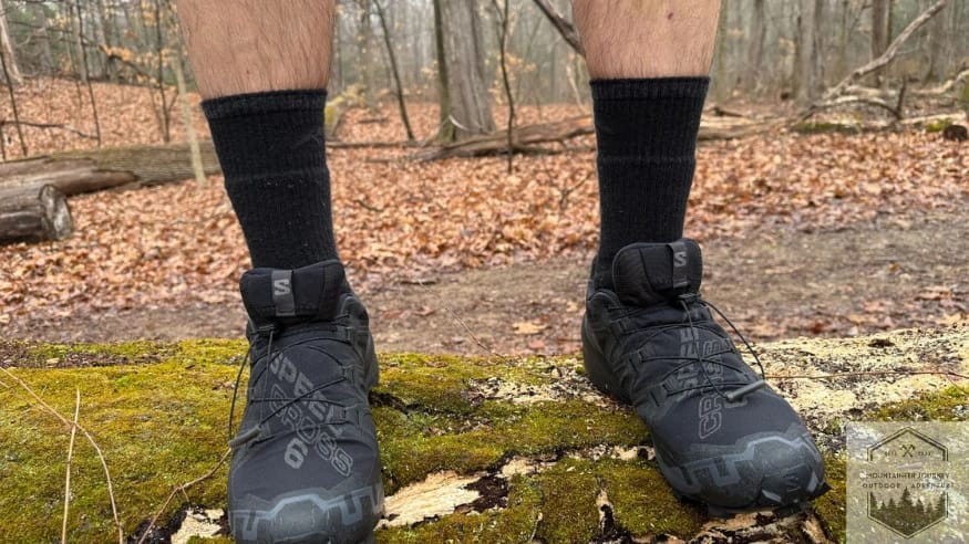 Frontal view of the Salomon Speedcross 6 during a log-balancing test, demonstrating the precise foothold of the SensiFit construction and the durability of the anti-debris ripstop mesh.