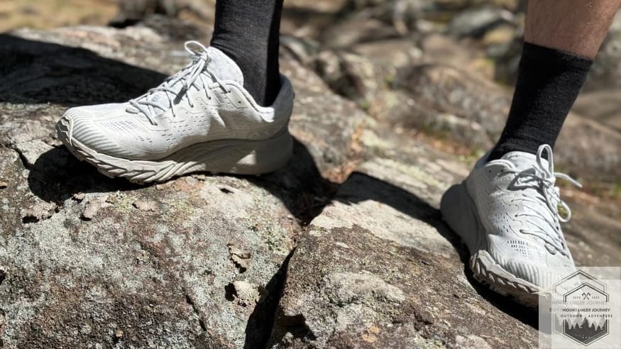 The Merrell Agility Peak 5 Vibram Megagrip outsole highlighting the aggressive forefoot traction lugs while standing on a rock.