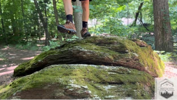 blog-img-1721426182538 Testing the Merrell Moab 3 stability on a moss-covered rock, evaluating the high-friction Vibram® TC5+ rubber compound's grip on wet, organic surfaces.