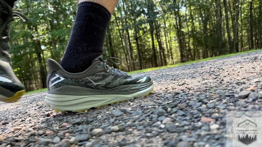 Action testing of the Hoka Stinson 7 on a gravel path, evaluating the H-Frame stability system and wide-base traction on shifting terrain.