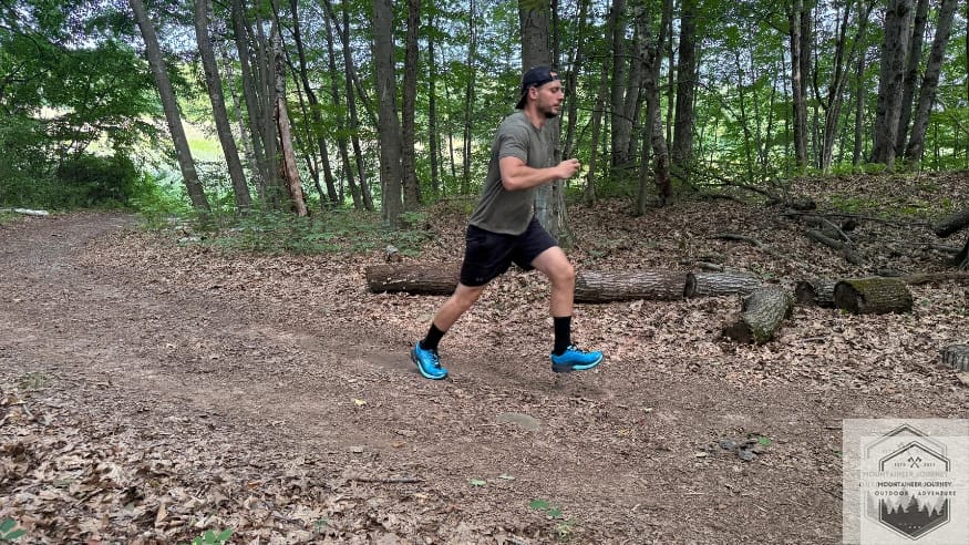 Side view of Hoka Mafate 5 trail running shoes in a wooded forest setting.