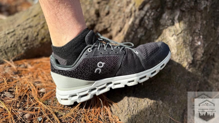 Side view of the On Cloud 6 resting against a tree trunk, showcasing the low-profile CloudTec pods and the sleek, breathable engineered mesh upper in a natural setting.