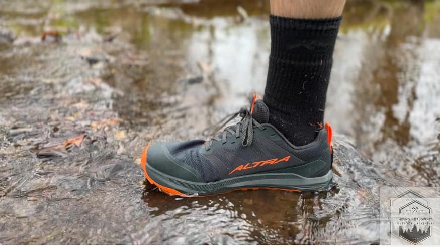 Standing in a river wearing trail shoes with a darn tough hiker, full cushion.