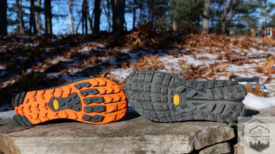 View of both shoes' outsoles sitting on a wall, both have Vibram Megagrip.