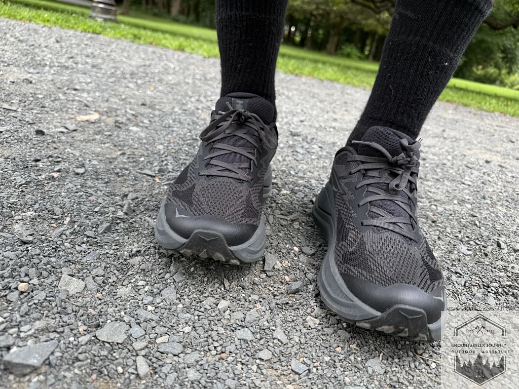 Front view of the Hoka Challenger 8 on a dirt trail, highlighting the breathable rPET engineered mesh upper and the protective 3D-printed toe cap overlays.