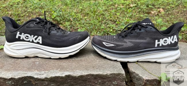 The Hoka Clifton 10(left) facing the Hoka Clifton 9(right) on a wall with grass behind them