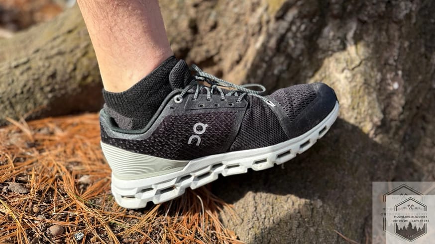 Side view of the On Cloud 6 resting against a tree trunk, showcasing the low-profile CloudTec pods and the sleek, breathable engineered mesh upper in a natural setting.