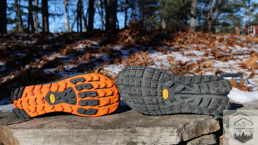 View of both shoes' outsoles sitting on a wall, both have Vibram Megagrip.