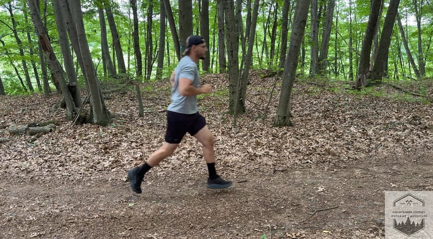 Actively testing the Hoka Challenger 8 on a technical trail, demonstrating the Meta-Rocker geometry's ability to facilitate a smooth, propulsive gait on uneven terrain.