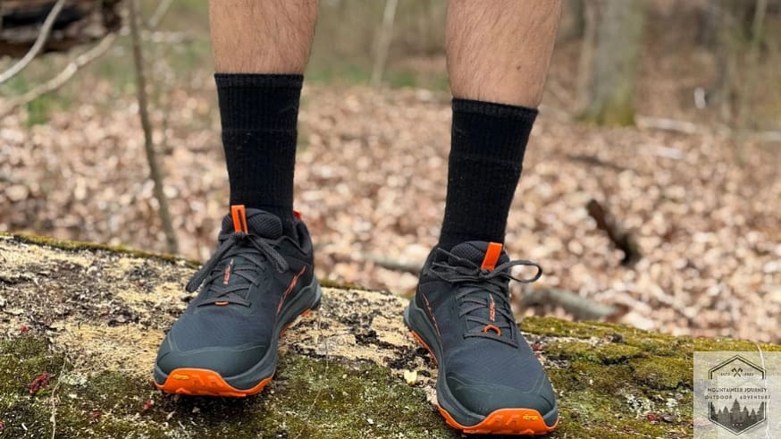 Altra Lone Peak 9+ being tested for stability and traction while standing on a fallen tree trunk.