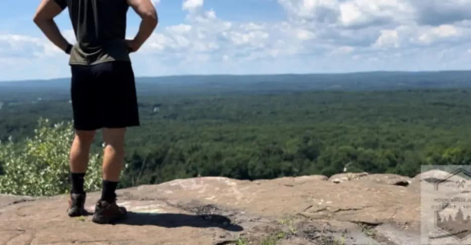 Summer Hiking Outfit: Moisture wicking shirt, shorts, summer hiking boots at the top of the summit